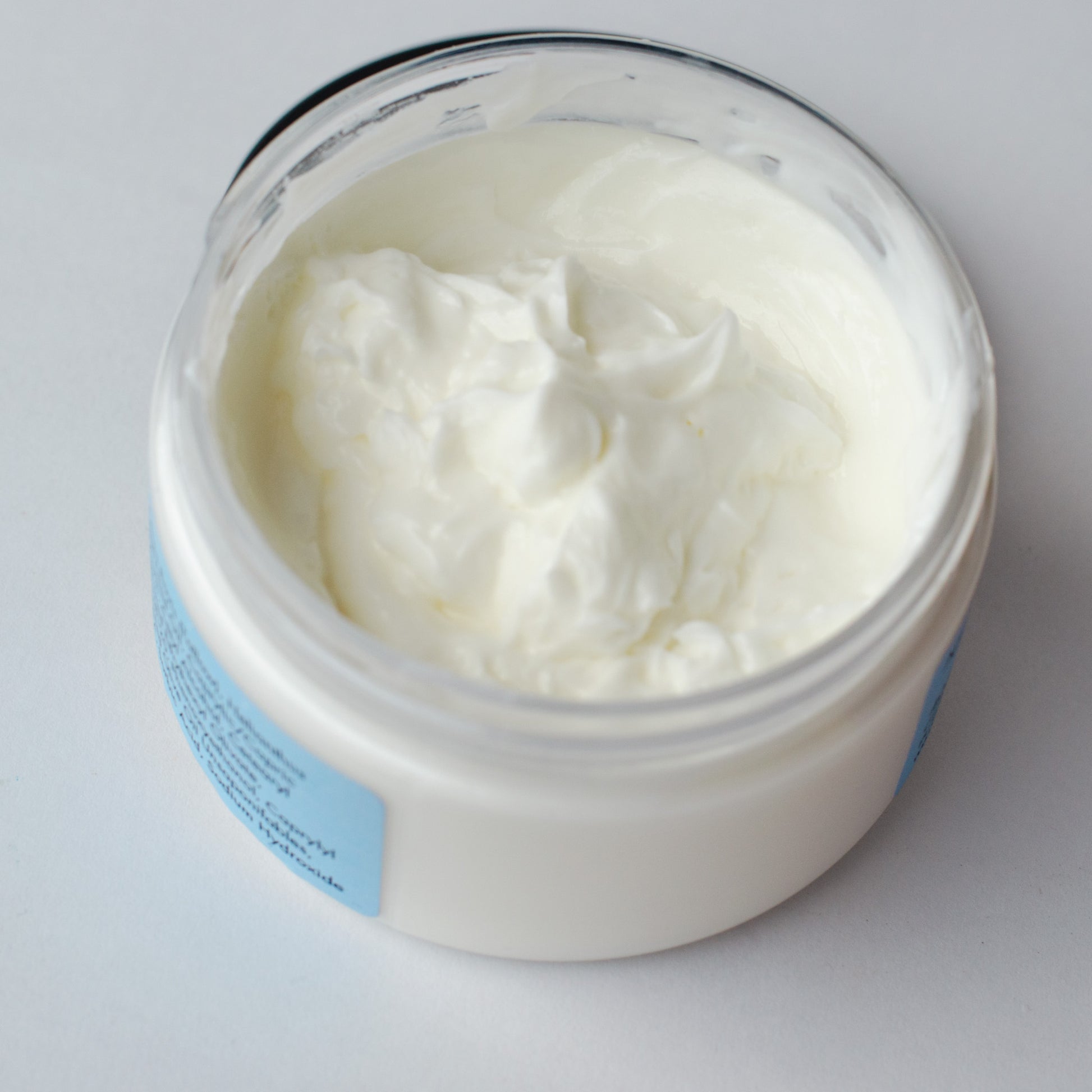 Tallow Body Creme jar with lid open to show cushy light texture. 